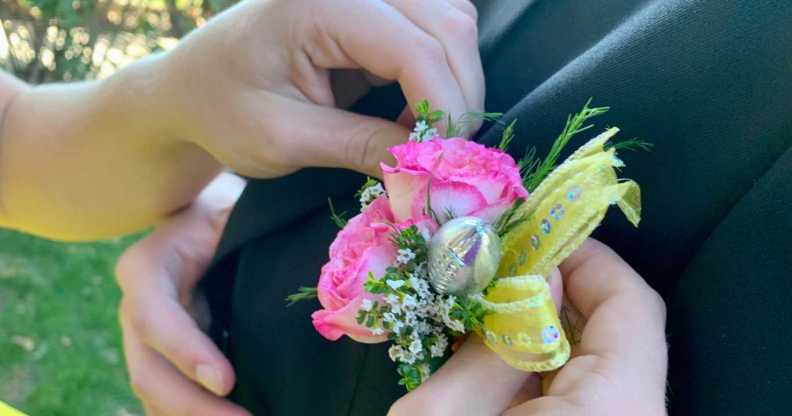 Teenage female, age 17-18, pinning floral boutonnière on Homecoming date suit lapel.