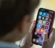 A child holding a mobile phone with social media icons on the sceen