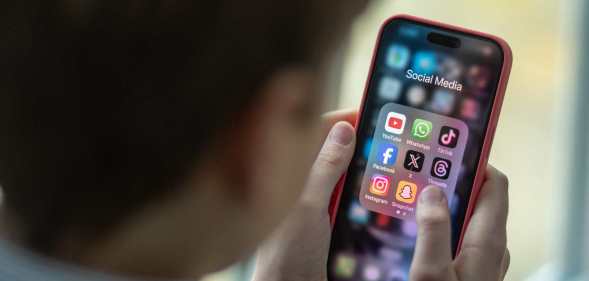 A child holding a mobile phone with social media icons on the sceen