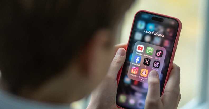 A child holding a mobile phone with social media icons on the sceen