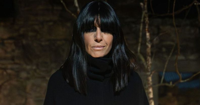 The Traitors host Claudia Winkleman in a black cape and black bangs that cover her eyes.