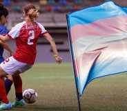 A still photograph of a female soccer defender in a blue uniform dribbling a soccer ball while an opposing attacker attempts to gain possession of the ball.