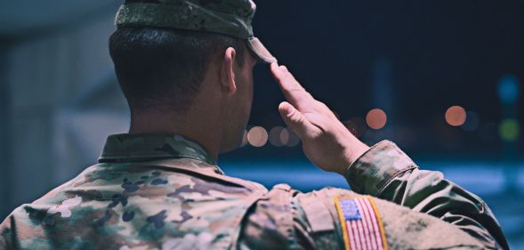 The back profile of a soldier saluting.