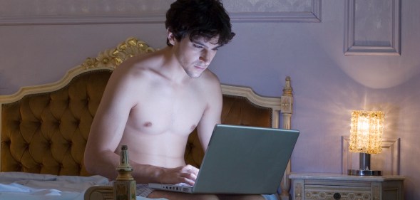 A shirtless man using a laptop computer