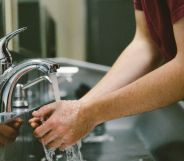 A person washing their hands in a public toilet.