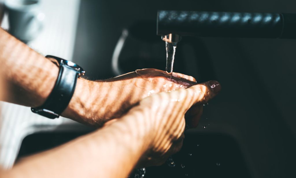 A person washing their hands in a bathroom.