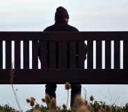 A man sits alone on a park bench.
