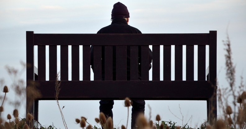 A man sits alone on a park bench.