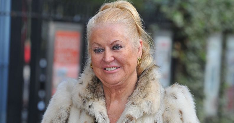 Kim Woodburn smiles while posing wearing a fur coat.