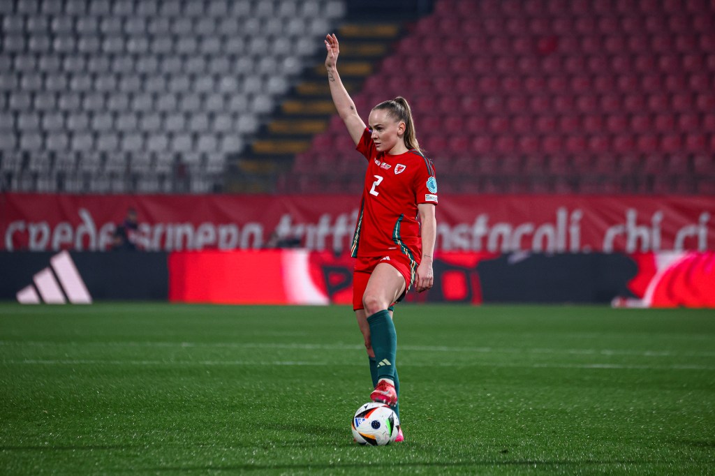 Lily Woodham of Wales gestures during the UEFA Women's Nations League. She wearing red top and shorts with green knee-high socks.