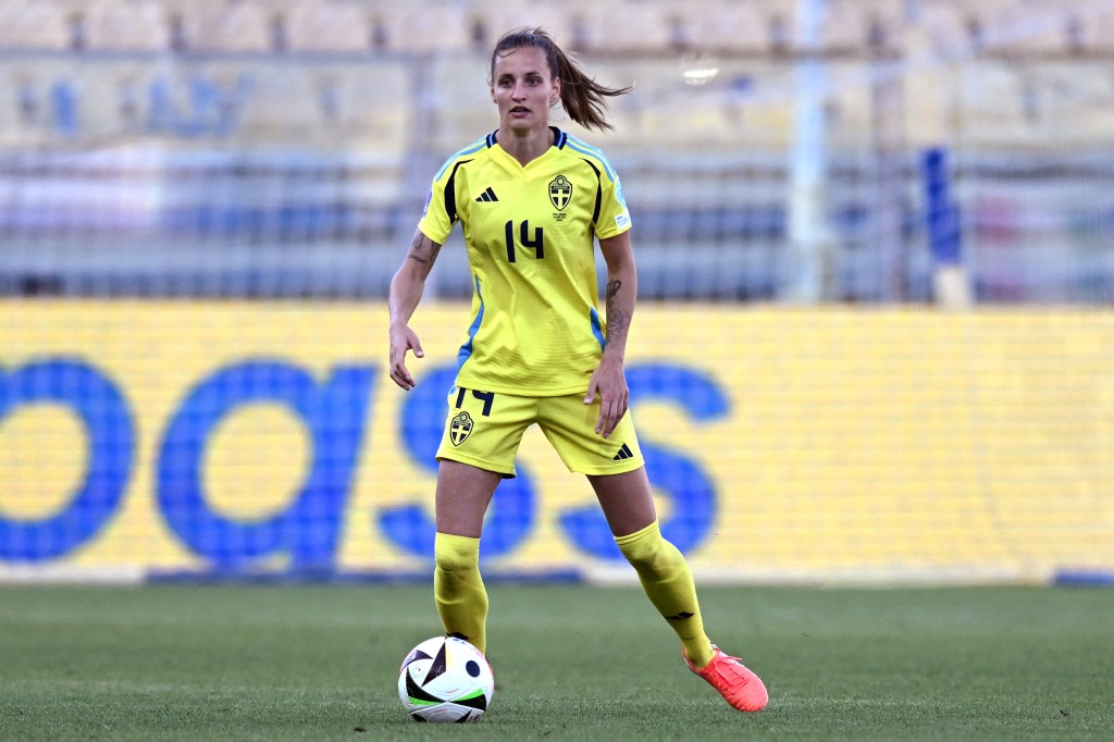 Nathalie Bjorn on the pitch in an all yellow kit dribbling the ball