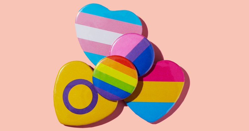 some different LGBTIQA badges, patterned with flags such as the lesbian flag, the transgender pride flag or the bisexual pride flag, on a pink background