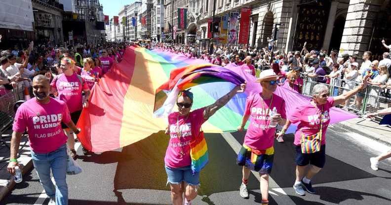 The rainbow flag is carried along Piccadilly by parade-goers during the 2024 Pride In London parade.