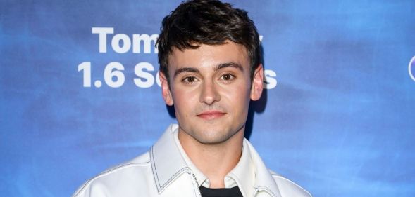 Tom Daley in a light jacket smiling as he poses at the premiere of his film 1.6 Seconds.