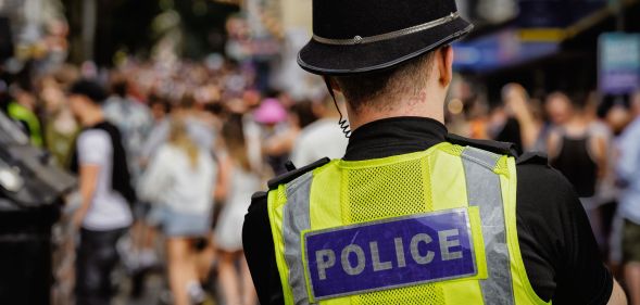 The back of a police officer looking at a crowd.