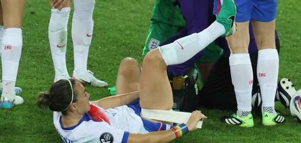 Lucy Bronze of England straps medical tape on her own leg as medical staff treat team mates Alex Greenwood and Hannah Hampton during the UEFA Women's EURO 2025 Quarter-Final match between Sweden and England