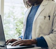 A doctor, face not pictured, typing on a laptop.