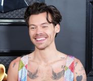 Harry Styles in a rainbow jumpsuit smiling.