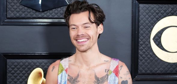 Harry Styles in a rainbow jumpsuit smiling.