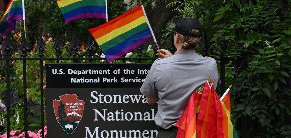 A staff member placing Pride flags on the Stonewall National Monument.