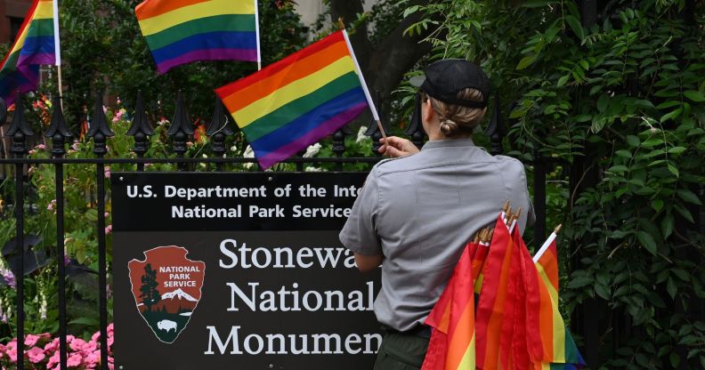 A staff member placing Pride flags on the Stonewall National Monument.