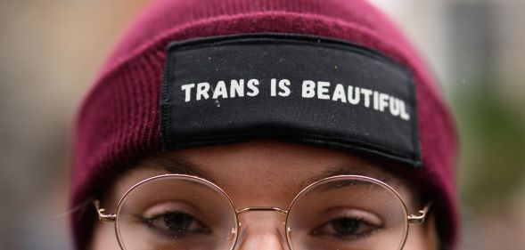 The upper-half of a person's head, wearing a hat that reads 'trans is beautiful'