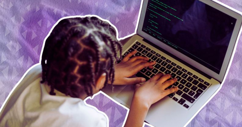 A kid sat on a bed on a laptop.