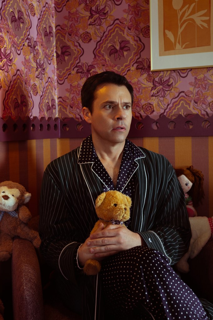 Bryan Safi wearing pyjamas and holding a teddy in a darkened room. He looks scared. 