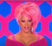 RuPaul on the Drag Rac judging panel in a pink outfit and pink wig with her mouth open.