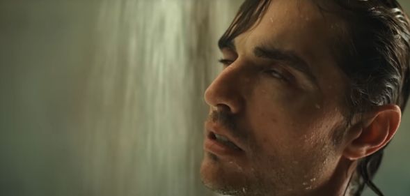 Dave Franco as Tim in horror movie Together. He is in the shower with wet slicked back brown hair, his eyes rolling back in his head.