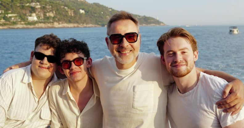Tobie Donovan, Joe Locke, David Walliams and Kit Connor pose together for a photo with the sea behind them. They are all in white wearing sunglasses, except for Kit Connor, with no sunglasses.