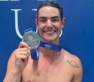 Drag Race star Gia Metric holding up their medal.