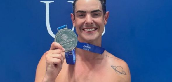 Drag Race star Gia Metric holding up their medal.