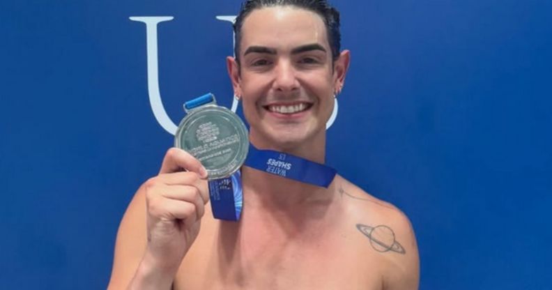 Drag Race star Gia Metric holding up their medal.