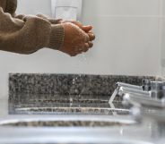 A person in a public bathroom washing their hands.
