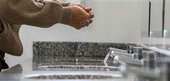 A person in a public bathroom washing their hands.