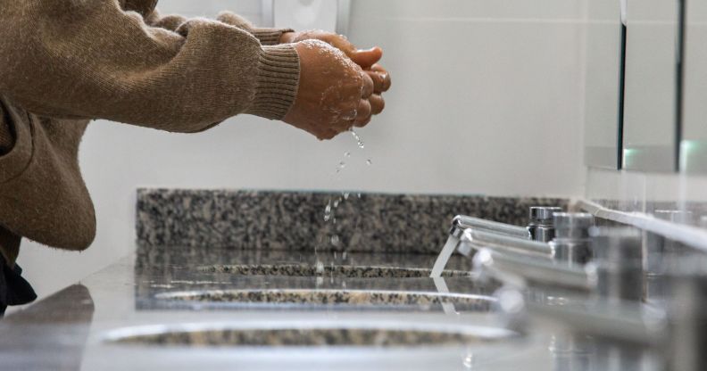 A person in a public bathroom washing their hands.