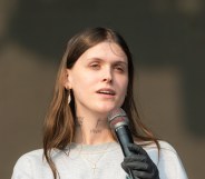 Ethel Cain performs during All Points East Festival. She's holding the mic, wearing a grey sweatshirt with a gold cross necklace.