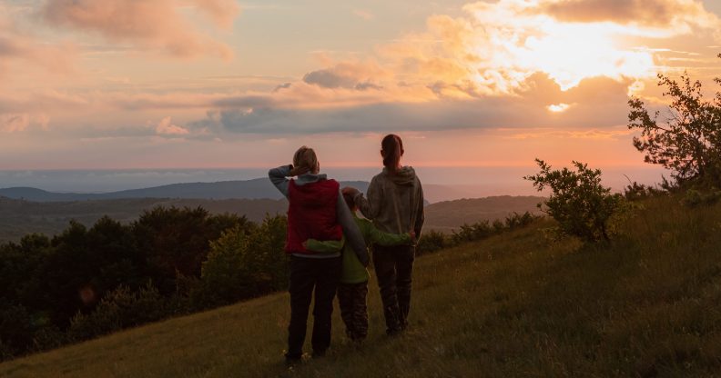 LGBTQ+ couple and child going for a walk during sunset.