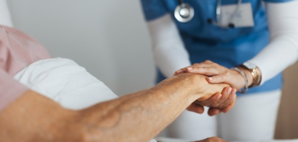 Close-up of caregiver holding senior client hand.