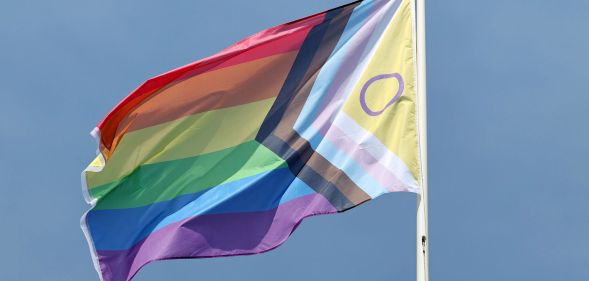 A Progress Pride flag on a flagpole.