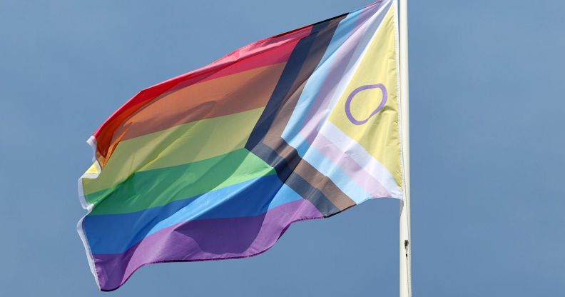 A Progress Pride flag on a flagpole.