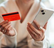 A person holding a phone and a credit card.