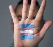 A person putting their hand up with trans flag colours on it.