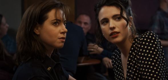 Aubrey Plaza and Margaret Qualley in Honey, Don’t. Plaza is in a police uniform and Qualley is in a polka dot black and white dress.