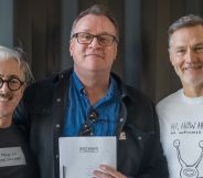A photo of Russell T Davies (C) smiling and holding a script for Tip Toe, with his arm around actors Alan Cumming (L) and David Morrissey.