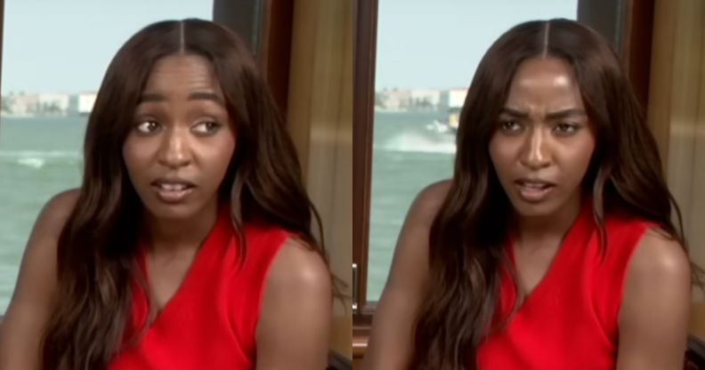 Ayo Edebiri looking shocked in a press junket. She is wearing a red top with her hair over her right shoulder.