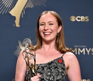 Hannah Einbinder holding her Emmy with a floral silver dress and red Artists4Ceasefire pin.