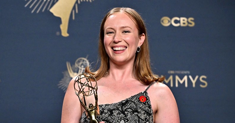 Hannah Einbinder holding her Emmy with a floral silver dress and red Artists4Ceasefire pin.