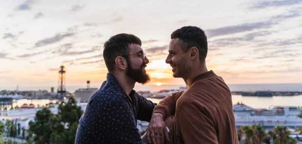 Gay couple on lookout above the city with view to the port, Barcelona, Spain.